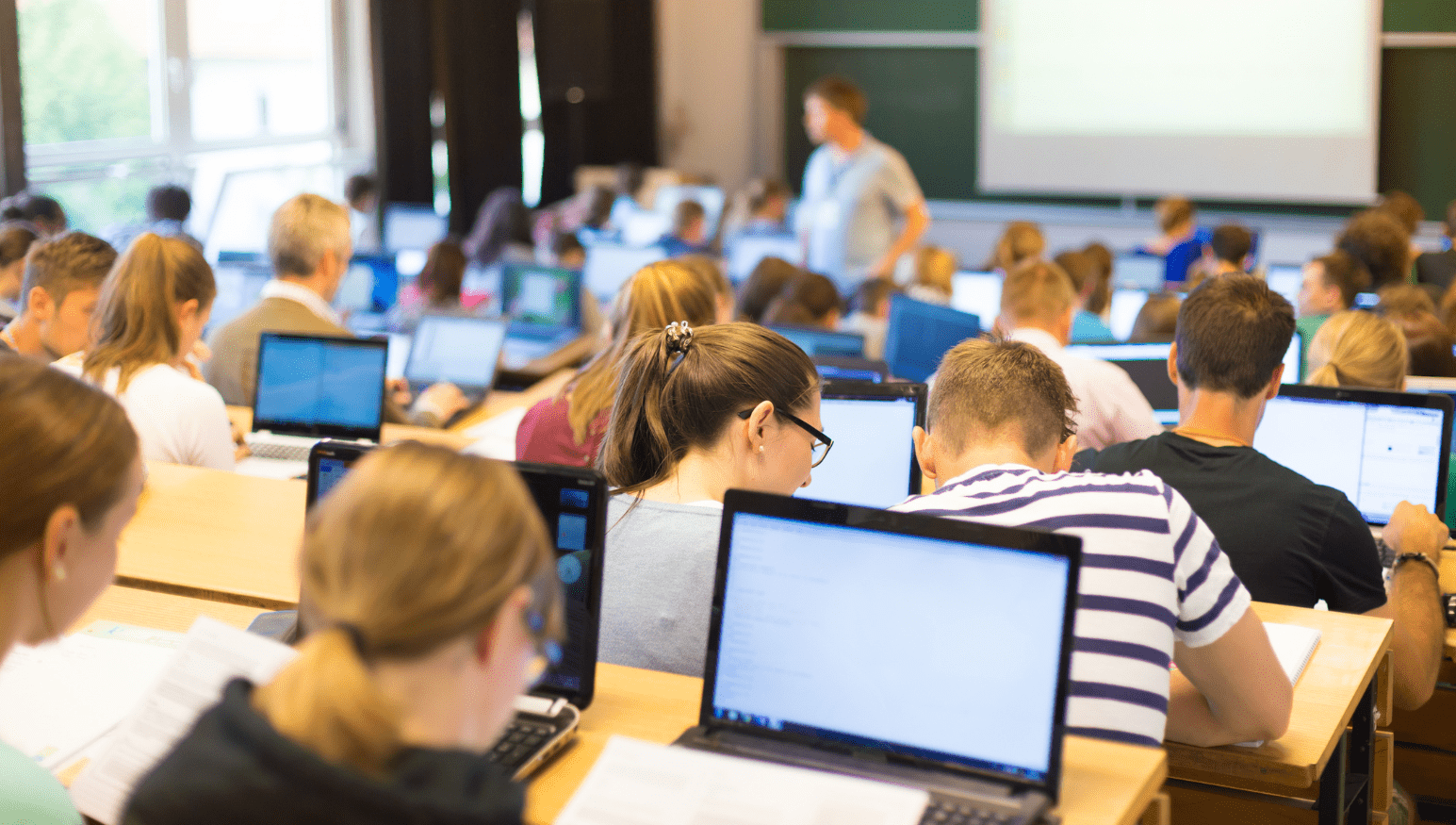 People at laptops in a lecture hall.