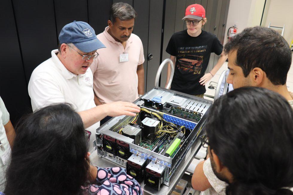 Man shows parts of the inside of a computer to other people.