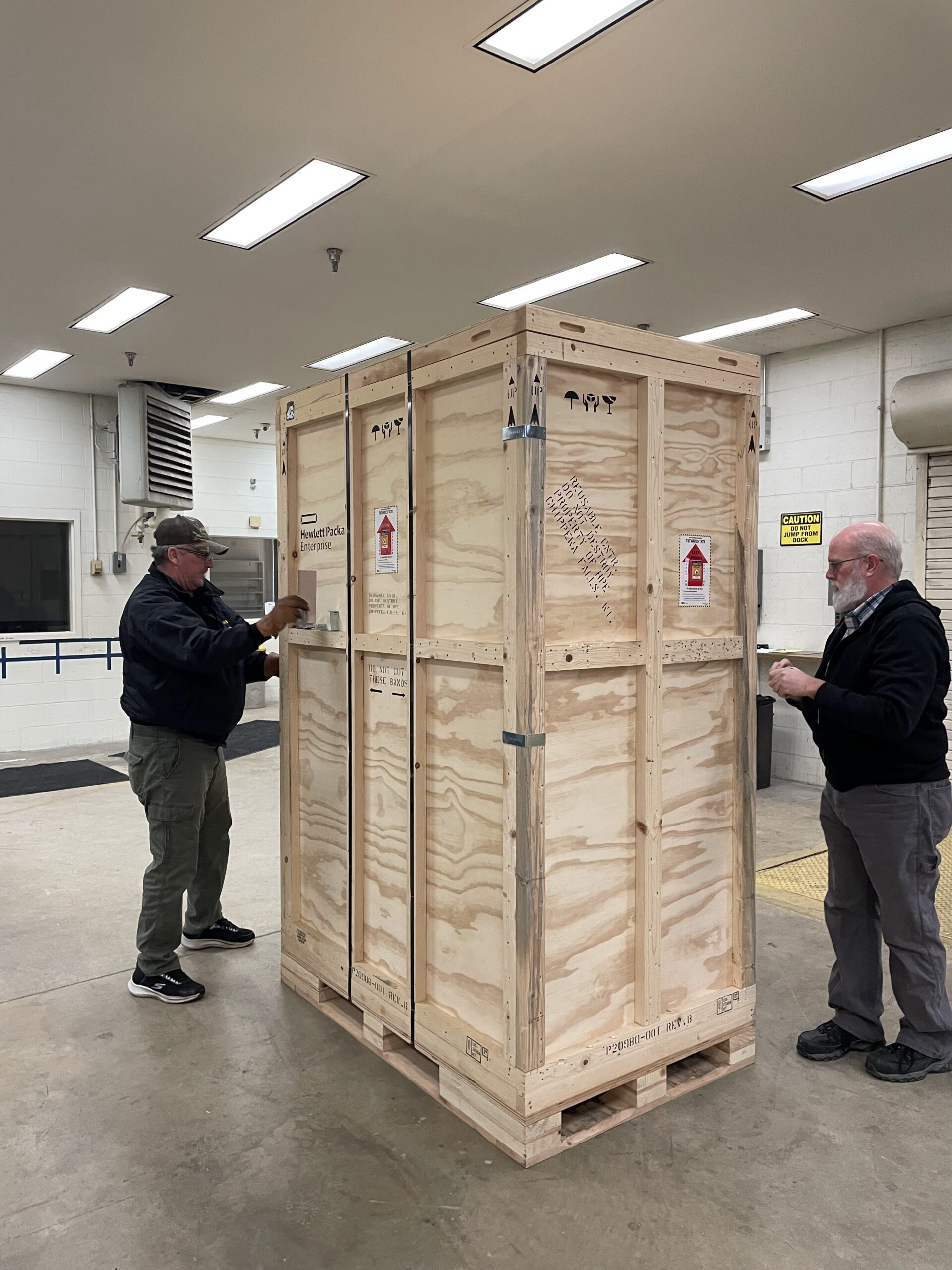 Two people with a large wooden delivery crate.