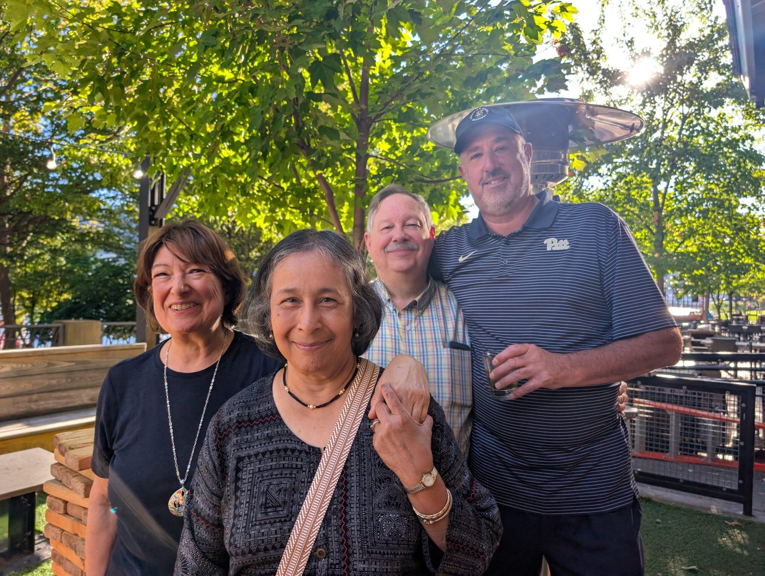 Four people smile for a group photo on a sunny day