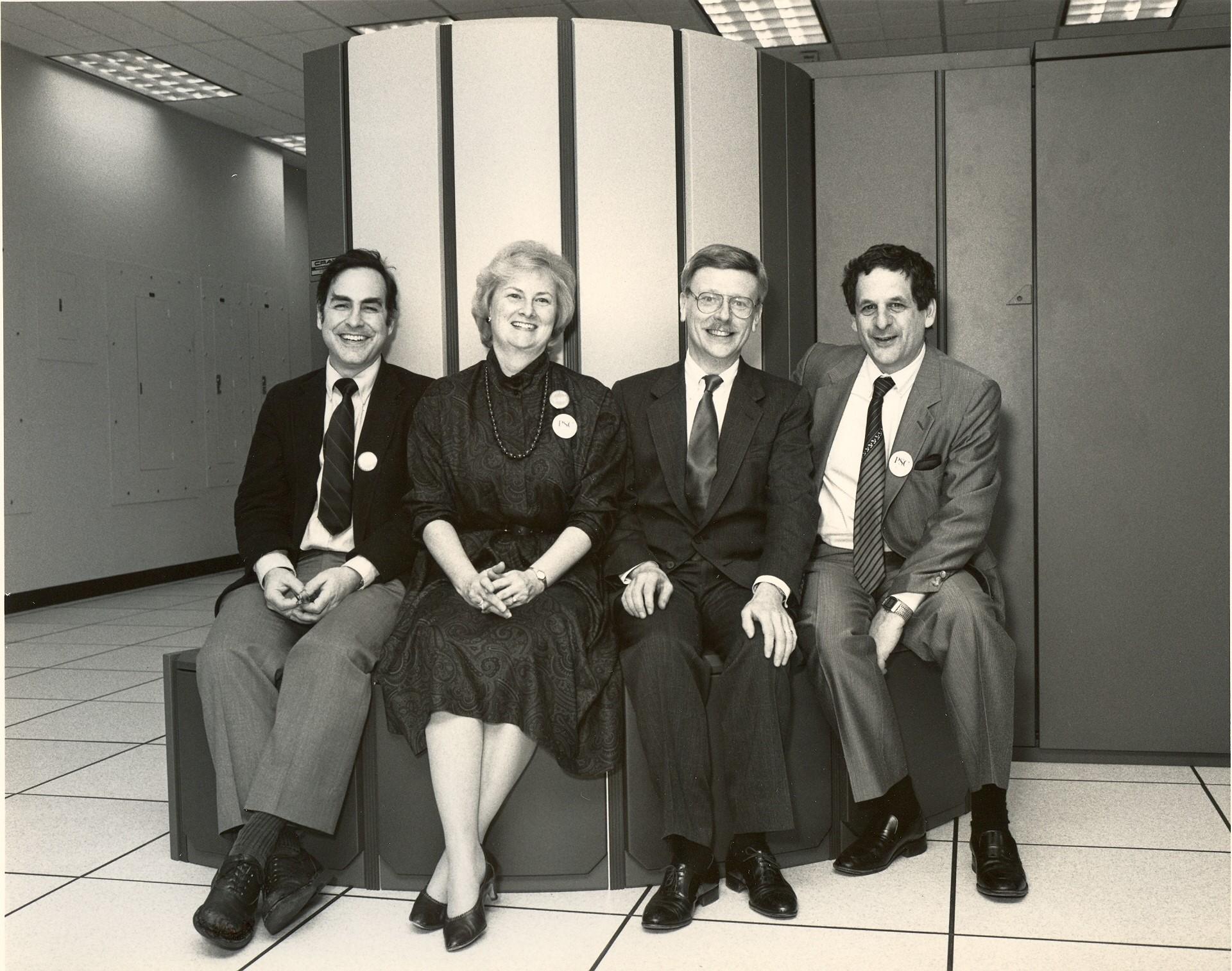 Four people sit on a supercomputer component.