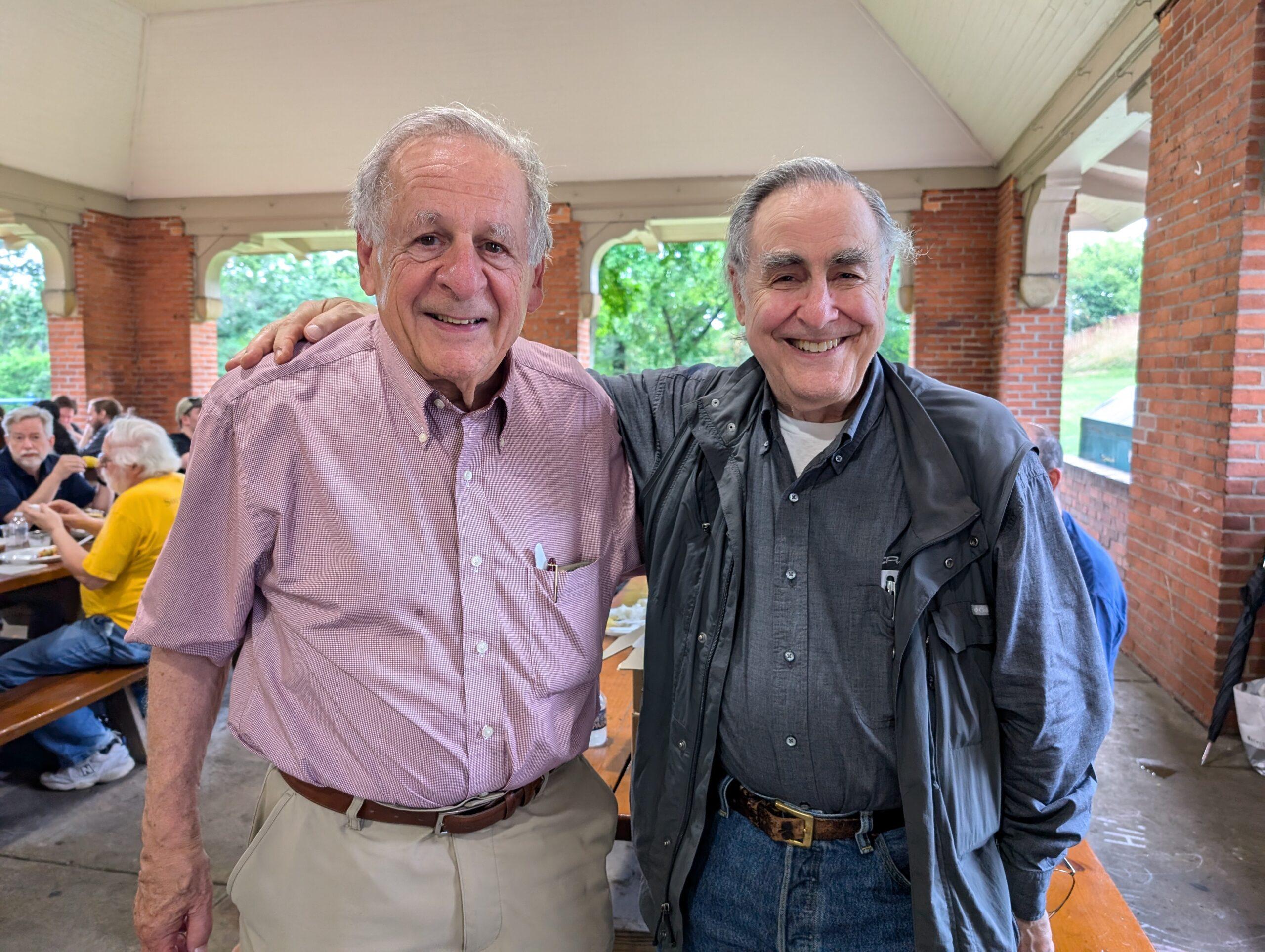 Two men smile at a picnic grove