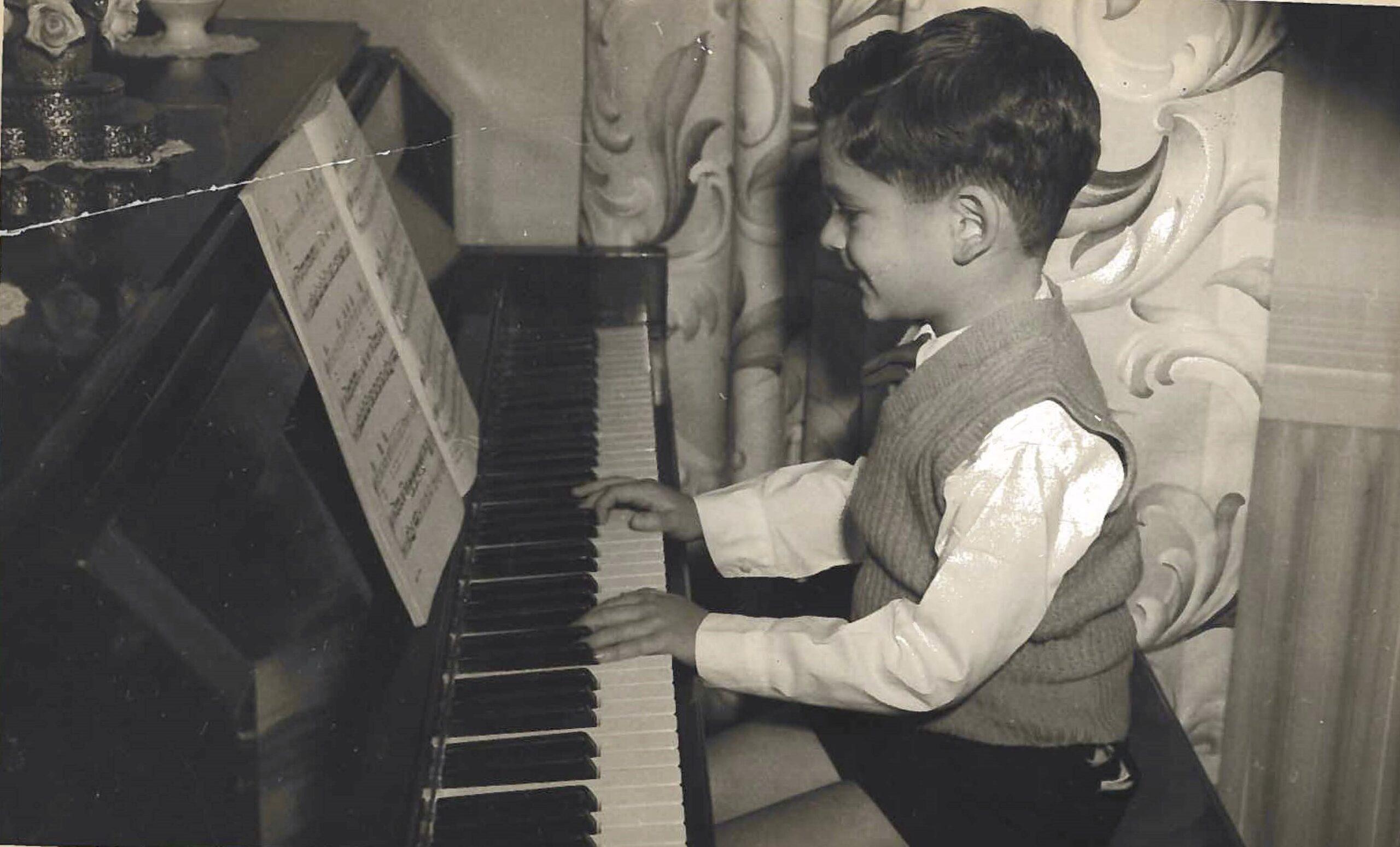 A young boy smiles at the piano