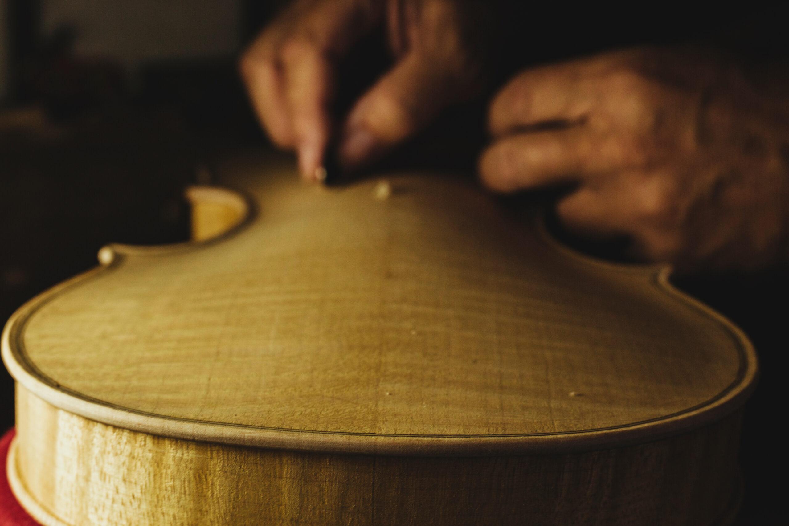 Close-up of the domed top plate of a violin being constructed. 