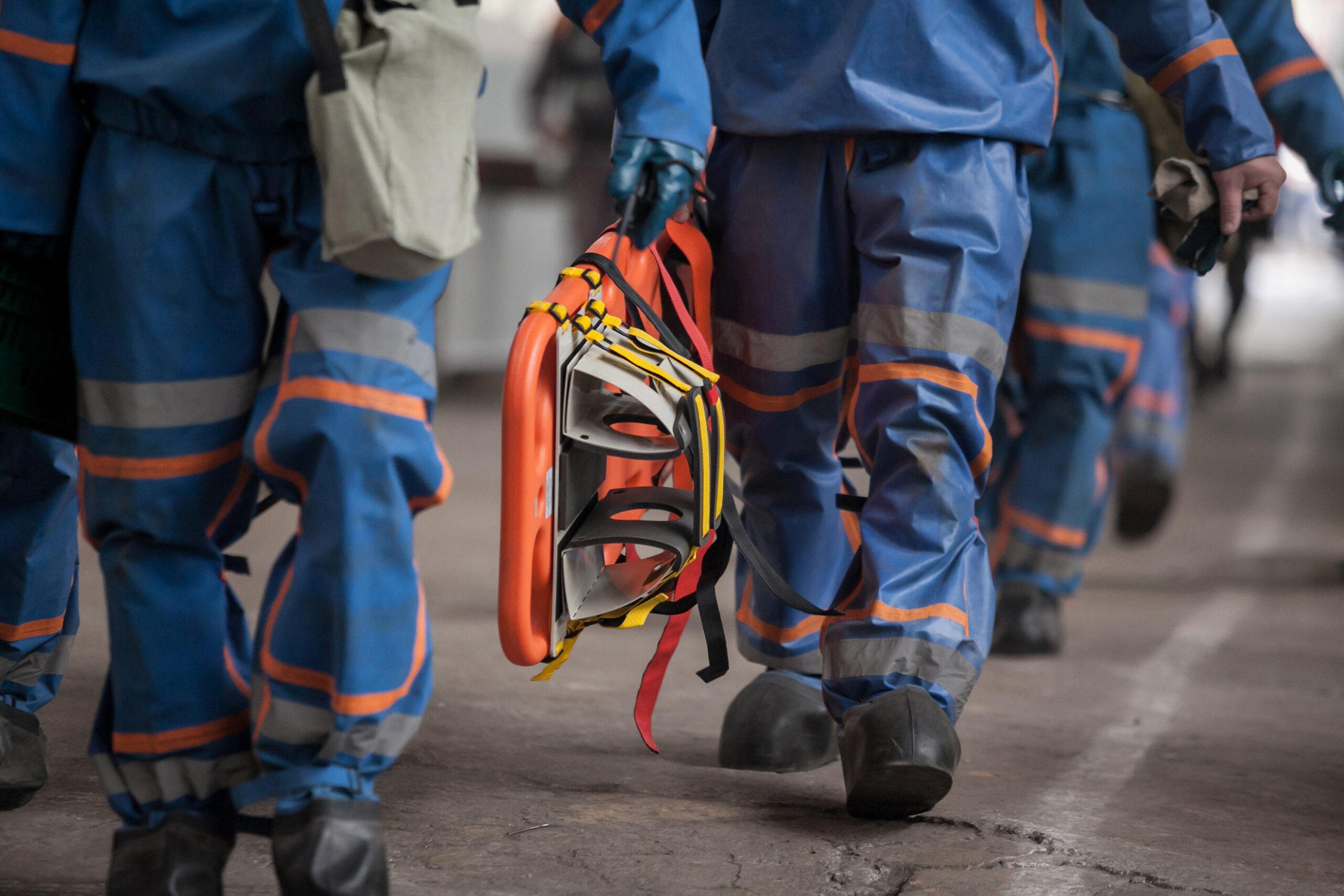 Emergency workers walking with a stretcher in hand in training exercise