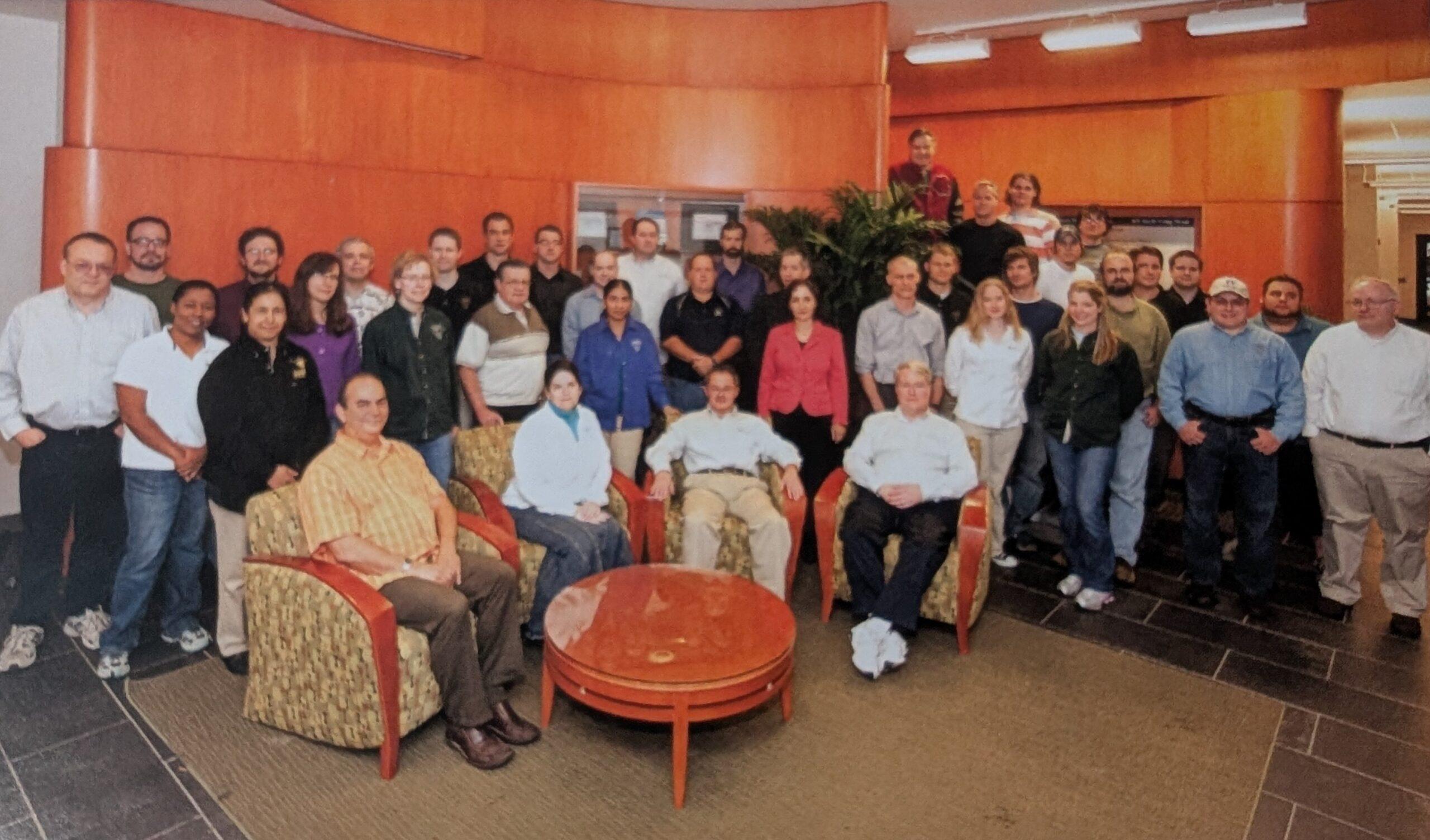 A large group photo of people in an office lobby. Among them is Robin Scibek.