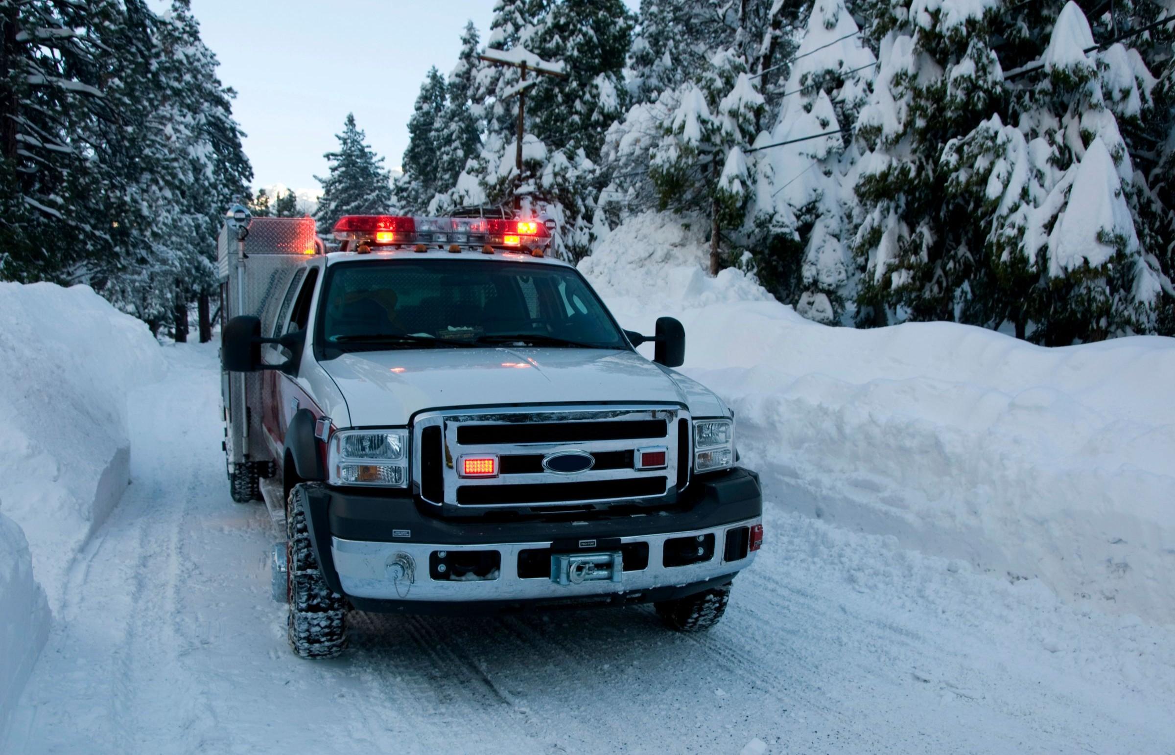 An emergency vehicle drives through the snow