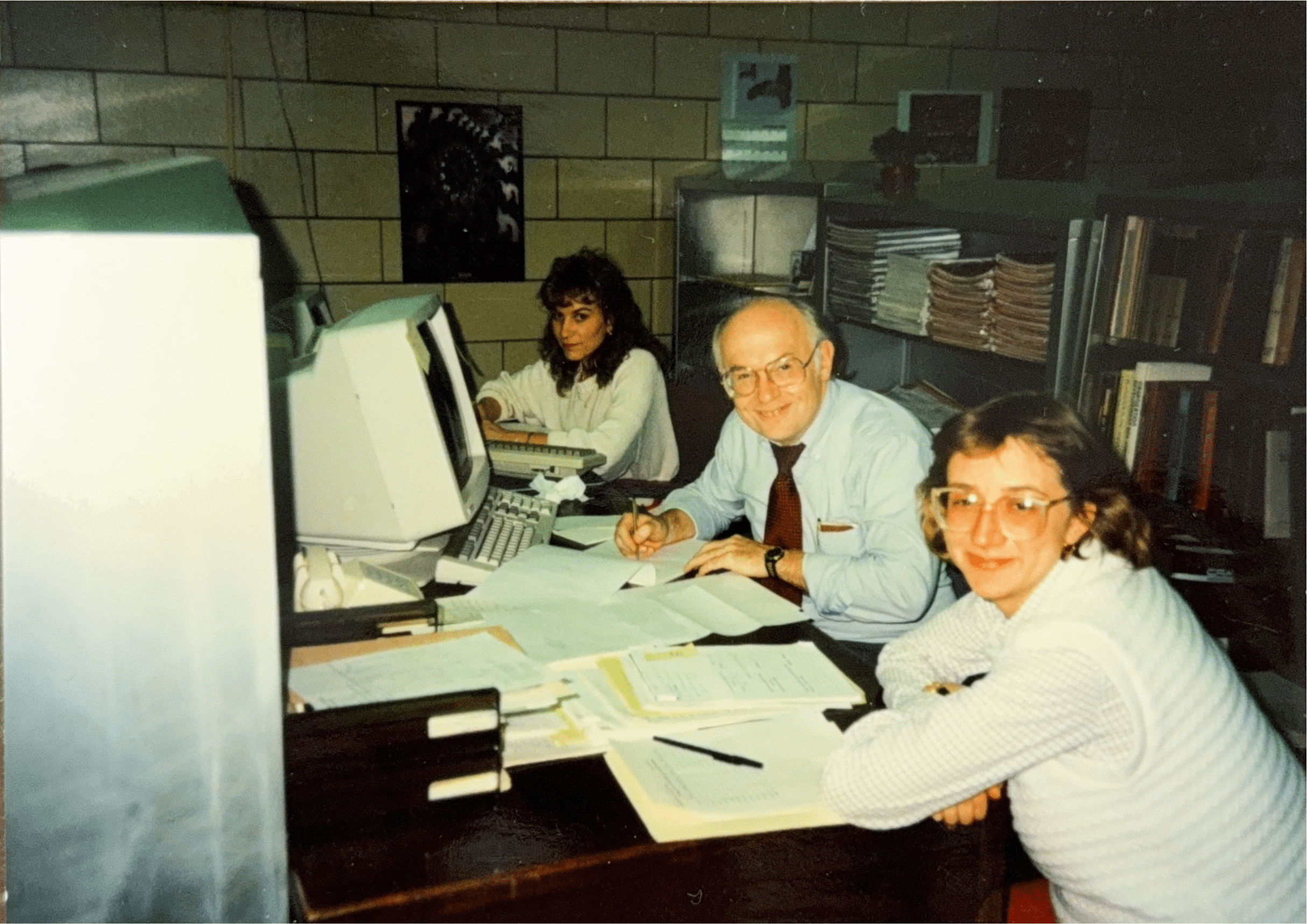 Three people sitting at a desk in front of a computer.