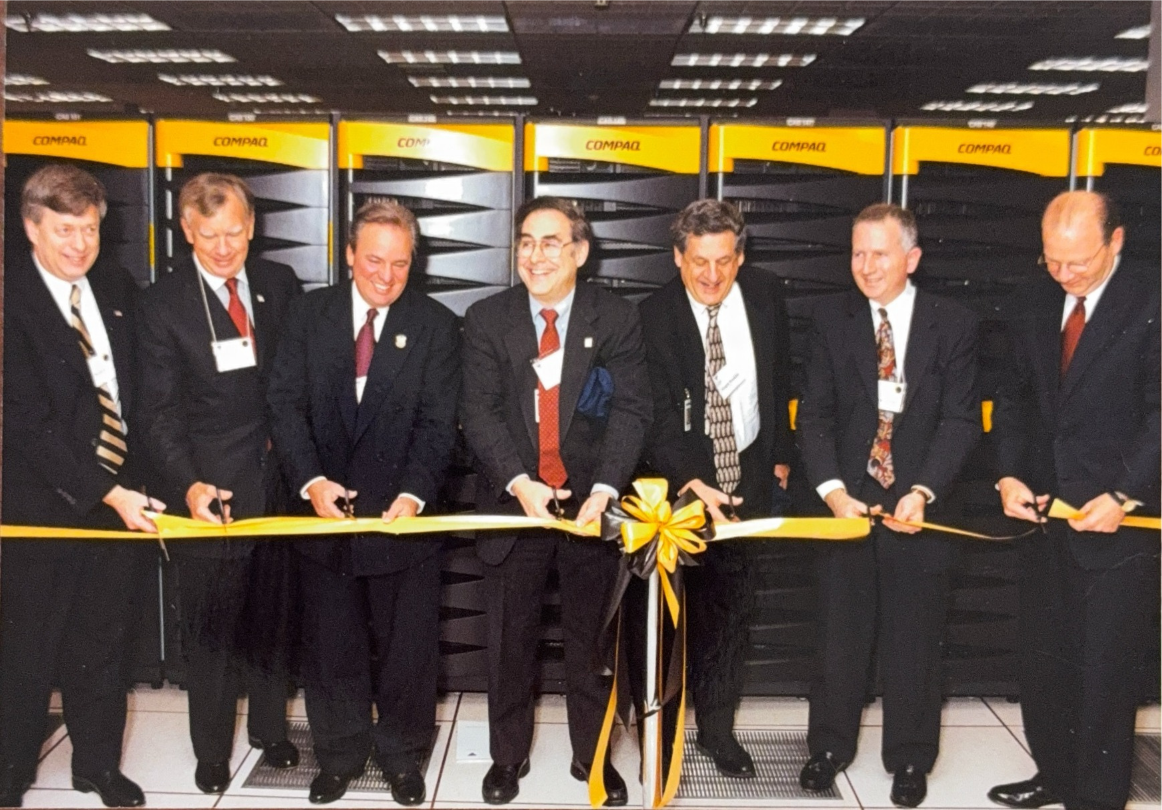 A group of men holding a ribbon and cutting it in a machine room.