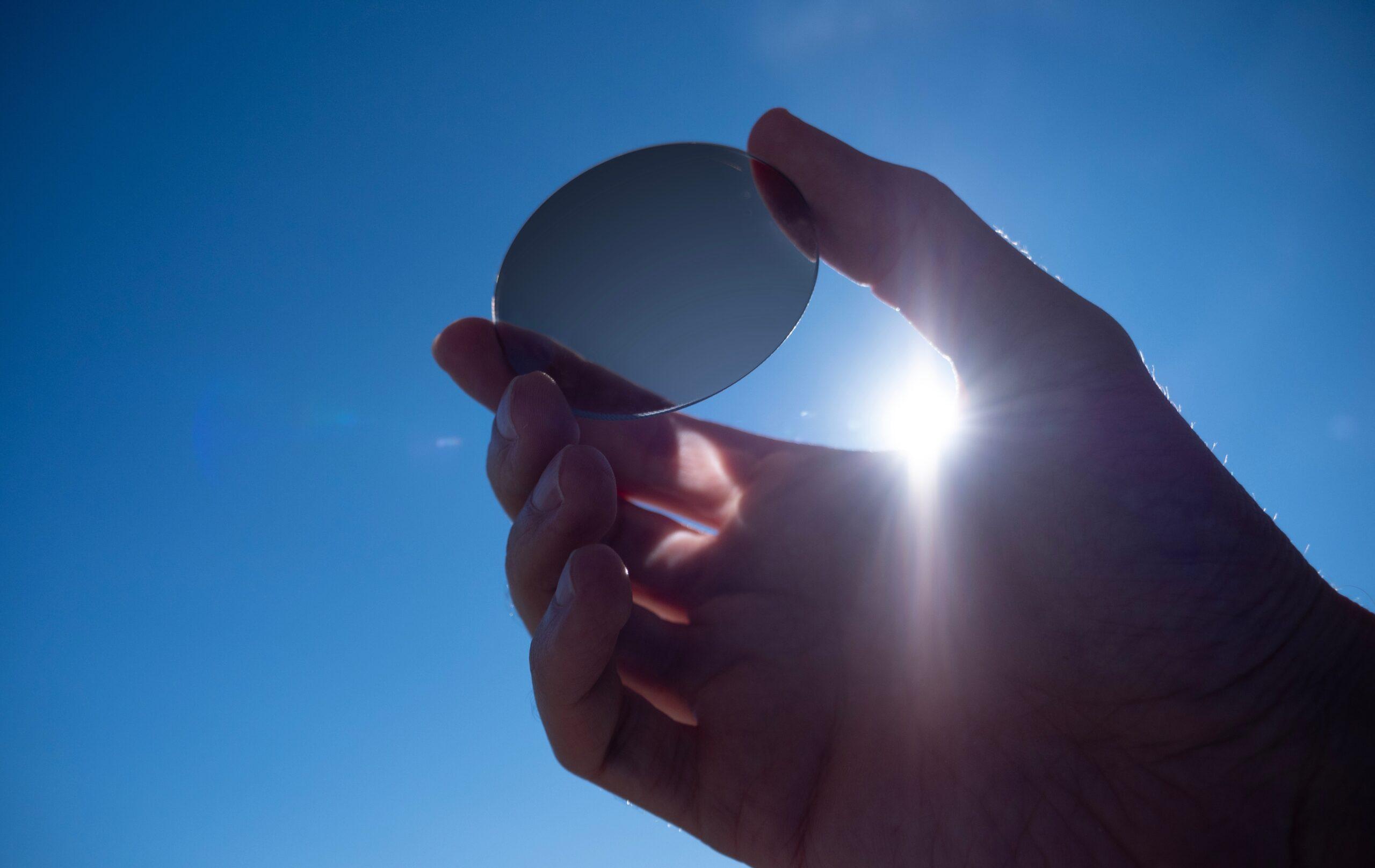 A hand holds a tinted lens to the sunny sky6